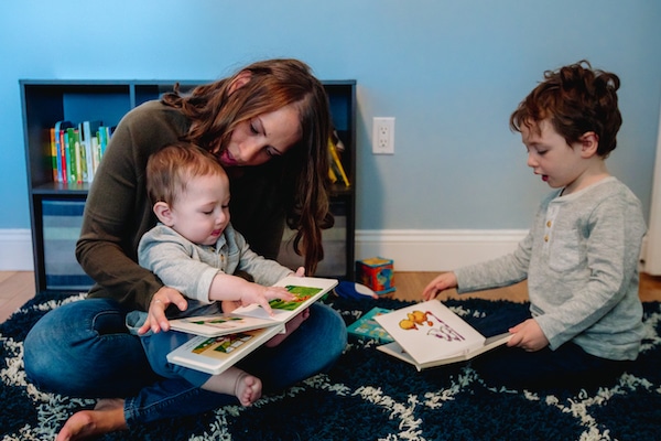 woman-reading-books-with-her-two-sons-her-infant-son-sitting-on-her-lap