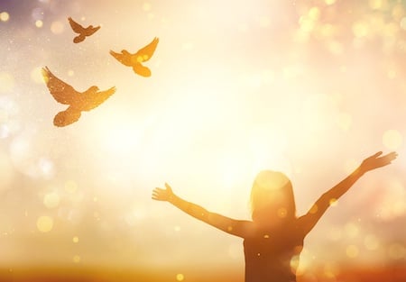 woman-standing-outside-in-the-sun-looking-up-with-arms-open-wide-looking-at-the-birds-flying-in-the-sky-finally-feeling-at-peace