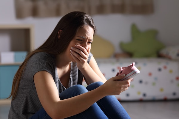 woman-crying-as-she-looks-at-a-baby-shoe