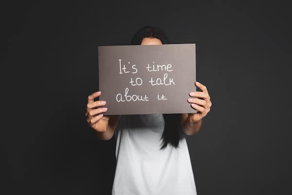 a-woman-holding-up-a-sign-that-says-it's-time-to-talk-about-it