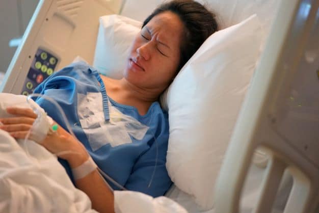 woman-sitting-in-a-hospital-bed-looking-like-she-is-in-pain-after-a-traumatic-birth