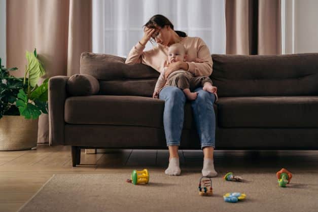 Mom-sitting-on-the-couch-looking-anxious-holding-her-baby