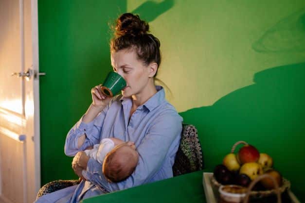 Mom-holding-her-baby-looking-exhausted-and-drinking-coffee
