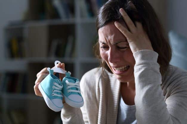 A-mother-holding-a-pair-of-baby-shoes-crying-over-the-loss-of-her-baby