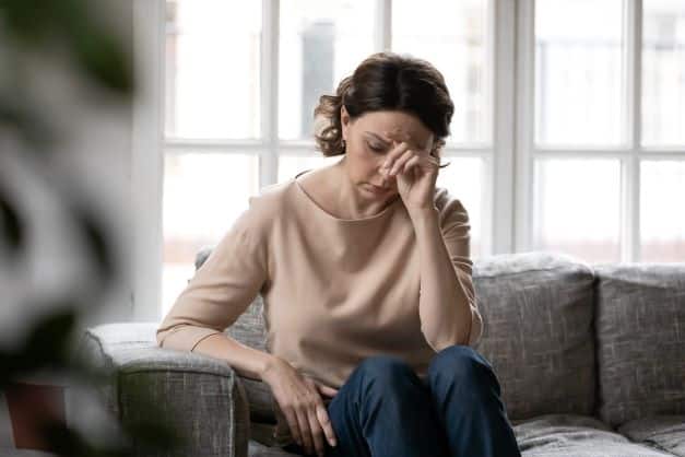 woman-sitting-on-the-couch-looking-overwhelmed-manaing-her-postpartum-depression