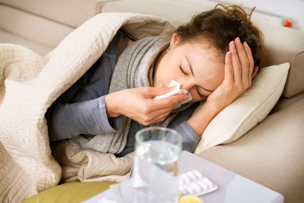 woman-lying-in-bed-sick-blowing-her-nose