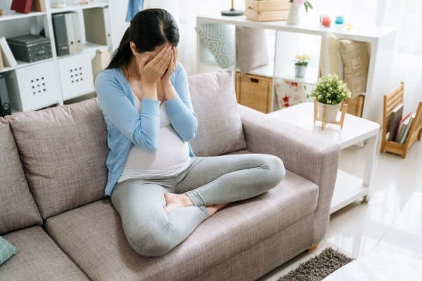 pregnant-woman-sitting-on-the-couch-cross-legged-feeling-anxious