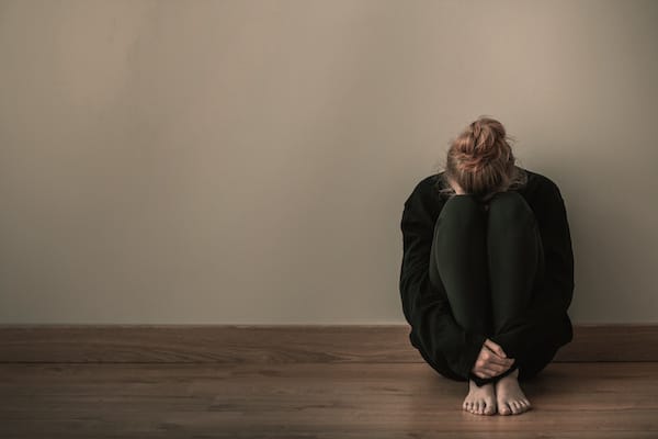 woman-sitting-on-the-floor-with-her-head-in-her-knees-looking-overwhelmed-due-to-postpartum-anxiety