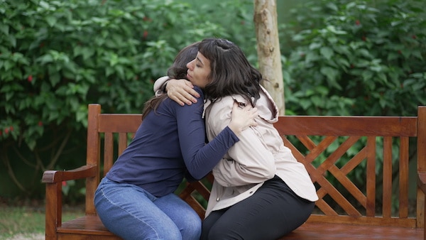 woman-sitting-on-a-park-bench-hugging-her-friend-to-get-support-from-grief