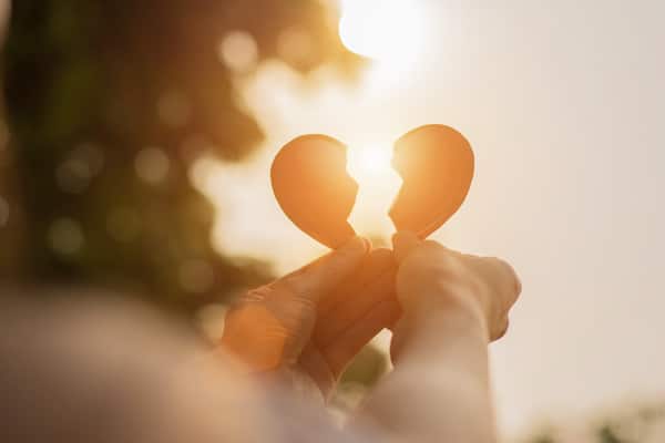 person-holding-a-broken-heart-up-to-the-sky-at-sunset